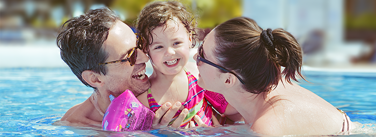 Los mejores hoteles Familiares, familia nadando en alberca de vacaciones en la playa